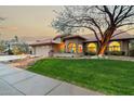Beautiful Southwestern home featuring a well-manicured lawn, mature tree, and cozy front porch area at 10105 E Larkspur Dr, Scottsdale, AZ 85260