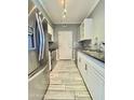 Galley kitchen features stainless steel appliances, light gray backsplash, and light grey floor tiles at 1701 E Colter St # 226, Phoenix, AZ 85016