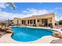 Resort-style backyard pool with rock features, lush landscaping, and a covered patio, perfect for outdoor entertaining and relaxation at 21842 E Via De Olivos --, Queen Creek, AZ 85142