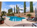Inviting backyard pool featuring a rock waterfall, tall cypress trees and relaxing lounge chairs on the deck at 21842 E Via De Olivos --, Queen Creek, AZ 85142