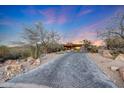 Elegant home with an extended paver driveway and serene desert landscaping, set against a vibrant sunset backdrop at 40915 N 107Th Pl, Scottsdale, AZ 85262