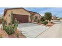Wide concrete driveway leading to a two-car garage, surrounded by desert landscaping and green cacti at 41737 W Cribbage Rd, Maricopa, AZ 85138