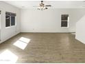 Spacious, well-lit living area with modern ceiling fan, neutral color palette, and wood-look flooring at 7009 W Lincoln St, Peoria, AZ 85345