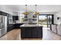 Modern kitchen boasts black cabinets, stainless steel appliances, marble counters, and an island overlooking water at 1700 E Lakeside Dr # 16, Gilbert, AZ 85234