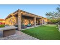 Beautiful backyard featuring a covered patio, built-in BBQ, putting green, and lush landscaping at 40930 N Lambert Trl, Phoenix, AZ 85086