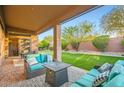 Relaxing covered patio with cozy seating, a fire pit, and a view of the lush backyard and putting green at 40930 N Lambert Trl, Phoenix, AZ 85086