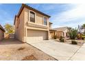 Side view of a two-story home with a desert landscape, showcasing the driveway and a peek into the backyard at 21397 N Goles Dr, Maricopa, AZ 85138