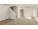 Bright living room with neutral carpet and white walls, featuring a staircase and archway at 21397 N Goles Dr, Maricopa, AZ 85138