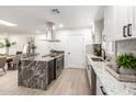 Bright kitchen features white cabinetry, stainless steel appliances, granite countertops, and an island with seating at 2142 E Palmcroft Dr, Tempe, AZ 85282