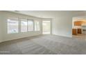 Bright living room with plush gray carpet, large windows, and view to the pool area at 22949 W Yavapai St, Buckeye, AZ 85326