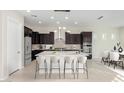Modern kitchen with dark cabinetry, stainless appliances, island with seating and pendant lights at 23072 N 98Th Dr, Peoria, AZ 85383