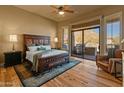 Comfortable main bedroom with hardwood floors, ceiling fan, and backyard access at 27561 N 84Th Dr, Peoria, AZ 85383