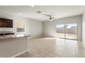 Open-concept living room features tile flooring, ceiling fan, and sliding glass door to backyard at 29909 N Yucca Dr, Florence, AZ 85132