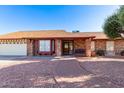 Single-story brick home features a well-maintained yard, attached garage, and brick walkway at 4323 W Villa Theresa Dr, Glendale, AZ 85308