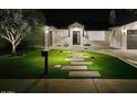 Night view of a beautifully landscaped single-story home with illuminated walkway and manicured lawn at 6325 N 83Rd Pl, Scottsdale, AZ 85250