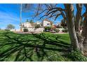 Well-maintained condo complex featuring manicured lawn, mature trees, and a bright red patio umbrella at 7800 E Lincoln E Dr # 1102, Scottsdale, AZ 85250