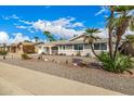 Single-story home with desert landscaping, mature palm trees, and a well-maintained lawn in a quiet neighborhood at 10846 W Crosby Dr, Sun City, AZ 85351