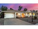 Single-story home featuring a white garage door, stucco exterior, and desert landscaping with a wide driveway at 10846 W Crosby Dr, Sun City, AZ 85351