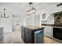 Kitchen island with gray countertop, black cabinets, beverage cooler, and modern pendant lighting at 1428 E Las Palmaritas Dr, Phoenix, AZ 85020