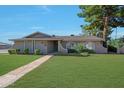 Attractive single-story home with a lush green lawn and mature trees in a desirable neighborhood at 1509 W Kiowa Ave, Mesa, AZ 85202