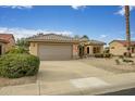 Charming home with a two-car garage, desert landscaping, and a lush green bush by the driveway at 16051 W Desert Winds Dr, Surprise, AZ 85374