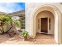 Elegant front entrance featuring an arched doorway, wood door, and lush landscaping at 30488 N 126Th Dr, Peoria, AZ 85383