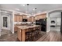 Modern kitchen featuring an island with seating, granite countertops, wood cabinets, and stainless steel appliances at 65 W Cucumber Tree Ave, San Tan Valley, AZ 85140