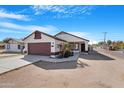 Charming single-story home features a red garage door and a well-maintained front yard, complemented by a clear blue sky at 7510 N 59Th Ln, Glendale, AZ 85301