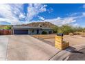 Single-story home featuring a two-car garage, desert landscaping, and a mailbox planter under a cloudy, blue sky at 9005 E Grandview Dr, Mesa, AZ 85207