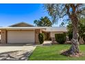 Charming single-Gathering home with a lush green lawn, mature trees, and a welcoming two-car garage at 12633 W Brandywine Dr, Sun City West, AZ 85375