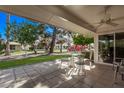 Relaxing covered patio with tiled floor, ceiling fan, and outdoor furniture overlooking a serene backyard at 12633 W Brandywine Dr, Sun City West, AZ 85375