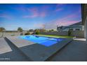 Beautiful in-ground pool offers a relaxing oasis in this backyard, set against a backdrop of vibrant sunset skies at 16832 E Hazeltine Way, Queen Creek, AZ 85142