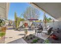 An inviting patio with a dining set, grill, lounge chairs, potted plants, and desert landscaping at 18614 N Conestoga Dr, Sun City, AZ 85373