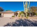 Inviting home with a three car garage surrounded by lush desert landscaping and a towering cactus at 18716 E White Wing Dr, Rio Verde, AZ 85263