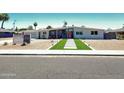 Daytime view of a mid-century modern home with desert landscaping and a vibrant orange front door at 2055 W Windsor Ave, Phoenix, AZ 85009