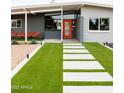 Close-up of the front entrance with a modern walkway, artificial turf, and bright orange door at 2055 W Windsor Ave, Phoenix, AZ 85009