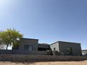 Contemporary home showcasing a sleek gray facade, complemented by desert landscaping and a low brick wall at 28304 N 141St Way, Scottsdale, AZ 85262