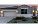 View of the inviting facade of this home featuring a garage and a front yard with decorative rock and desert shrubs at 30071 W Indianola Ave, Buckeye, AZ 85396
