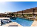 Beautiful backyard pool with desert mural on the wall, lounge chairs, and covered patio at 3202 N 197Th Ave, Buckeye, AZ 85396
