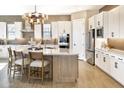 Bright kitchen featuring white cabinets, a marble-top island with seating, stainless steel appliances, and decorative lighting at 5719 S Quartz St, Gilbert, AZ 85298