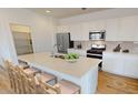 Modern kitchen featuring white cabinets, stainless steel appliances, a large island with seating, and stylish backsplash at 12547 W Parkway Ln, Avondale, AZ 85323