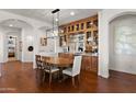 Elegant dining room featuring a modern chandelier and a built-in dry bar with glass shelving at 1275 E Verde Blvd, Queen Creek, AZ 85140