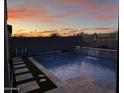 Backyard pool area with a modern design, featuring a waterfall feature and serene landscaping at 17496 W Summit Dr, Goodyear, AZ 85338