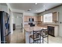 Bright kitchen featuring a center island with granite countertops and modern appliances and tile flooring at 40716 N Hudson Trl, Anthem, AZ 85086