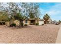 Single story home with desert landscaping in the front yard and large shade tree at 5226 W Freeway Ln, Glendale, AZ 85302