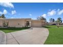 Beige single-story home with a well-maintained lawn, desert plants, a curved driveway, and a two-car garage at 8165 E Del Marino Dr, Scottsdale, AZ 85258