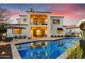 Beautiful backyard with a refreshing blue pool, dining, lounge furniture, and a two-story white stucco home at 9467 E Rockwood Dr, Scottsdale, AZ 85255