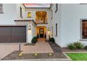 Elegant home entrance featuring a small balcony, dark wood doors with brick-paved walkway, desert foliage, and green lawn at 9467 E Rockwood Dr, Scottsdale, AZ 85255