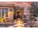 Inviting home exterior with illuminated entry stairs, desert landscaping, and a charming front gate at 1407 E Artemis Trl, San Tan Valley, AZ 85140