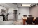 Modern kitchen flows into the dining area with stainless steel appliances, white cabinetry, and a marble-topped dining table at 16402 N 31St St # 102, Phoenix, AZ 85032